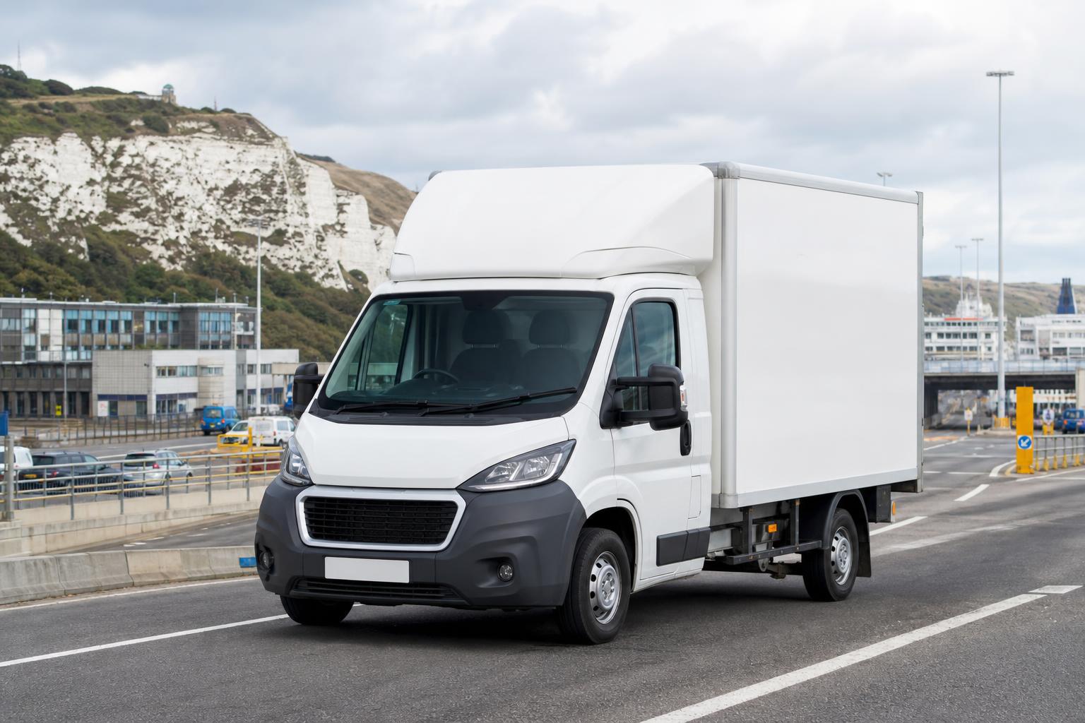 White box van on a road near Dover with port-town surroundings and chalk hillside in the distance